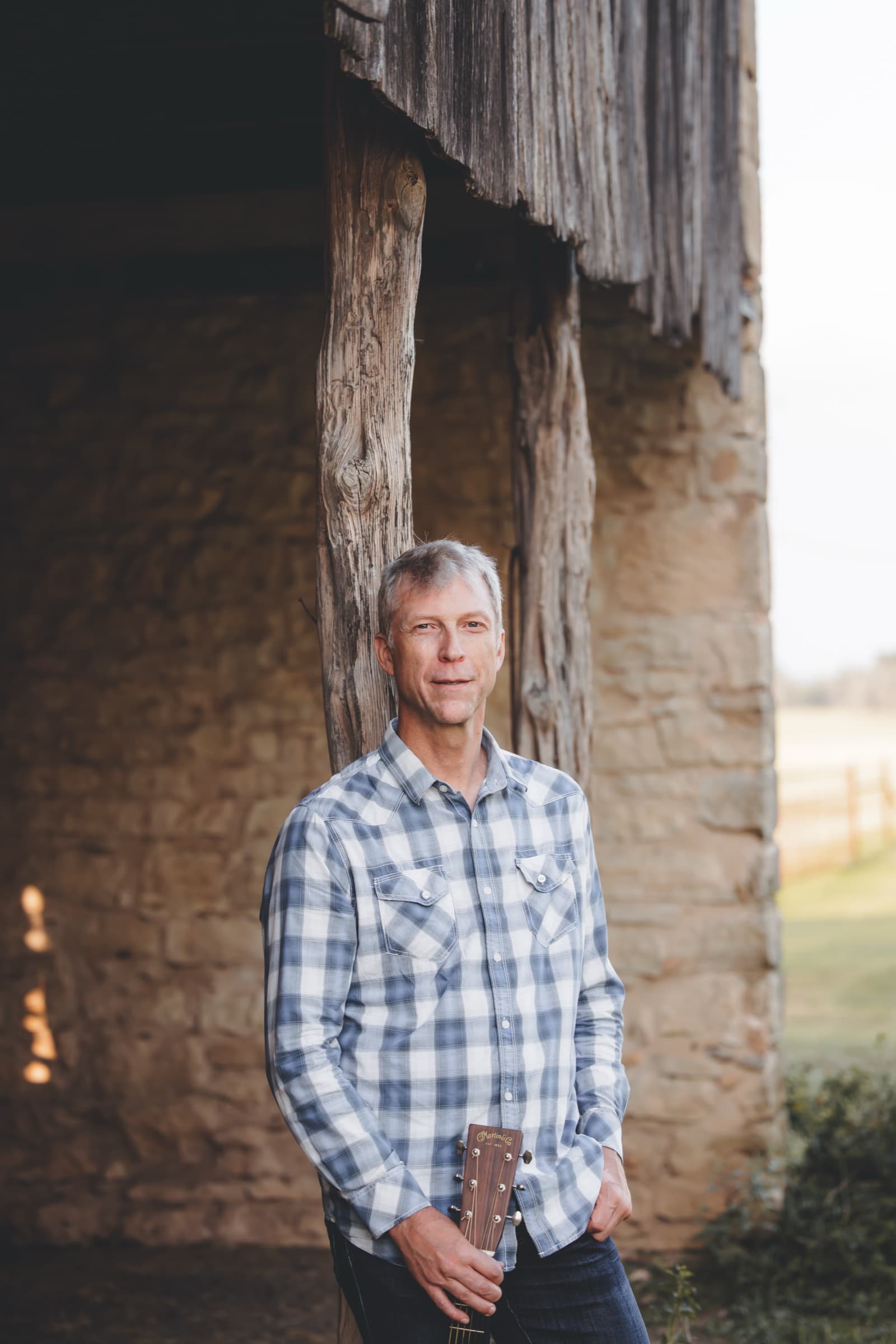 Portrait of Ian leaning against a weathered cedar post